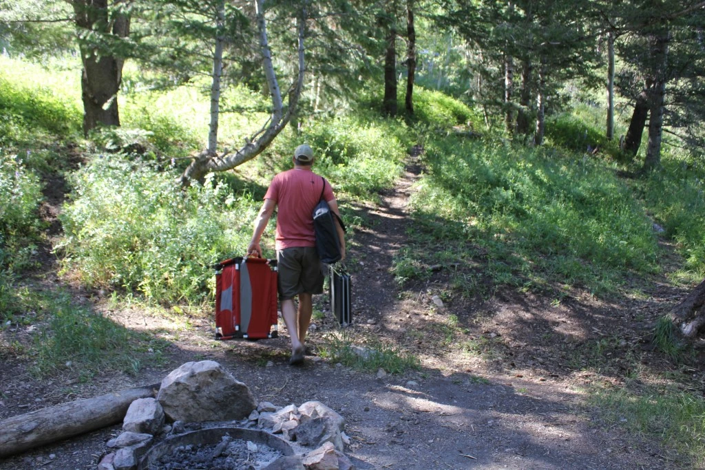 camping table - reviewer jason wanlass toting several tables for testing.